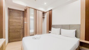 A hotel room with a large bed, wooden wardrobe, and a built-in closet. - Comfort Living 2Br At Sky House Bsd Apartment (Pagedangan)