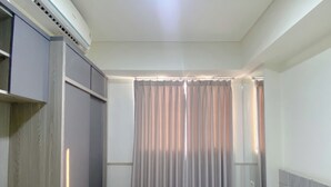 A hotel room with a bed, a wardrobe, and a window with curtains. - Well Furnished And Comfortable 2Br Meikarta Apartment (Cikarang)