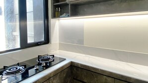 A kitchen with a gas stove, a window, and a tiled backsplash. - Well Furnished And Comfortable 2Br Meikarta Apartment (Cikarang)