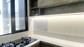 A kitchen with a gas stove, a window, and a tiled backsplash.