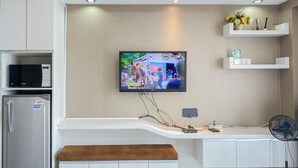 Ett modernt kök med en inbyggd mikrovågsugn, ett kylskåp, en platt-TV som är monterad på väggen och en träbänk.