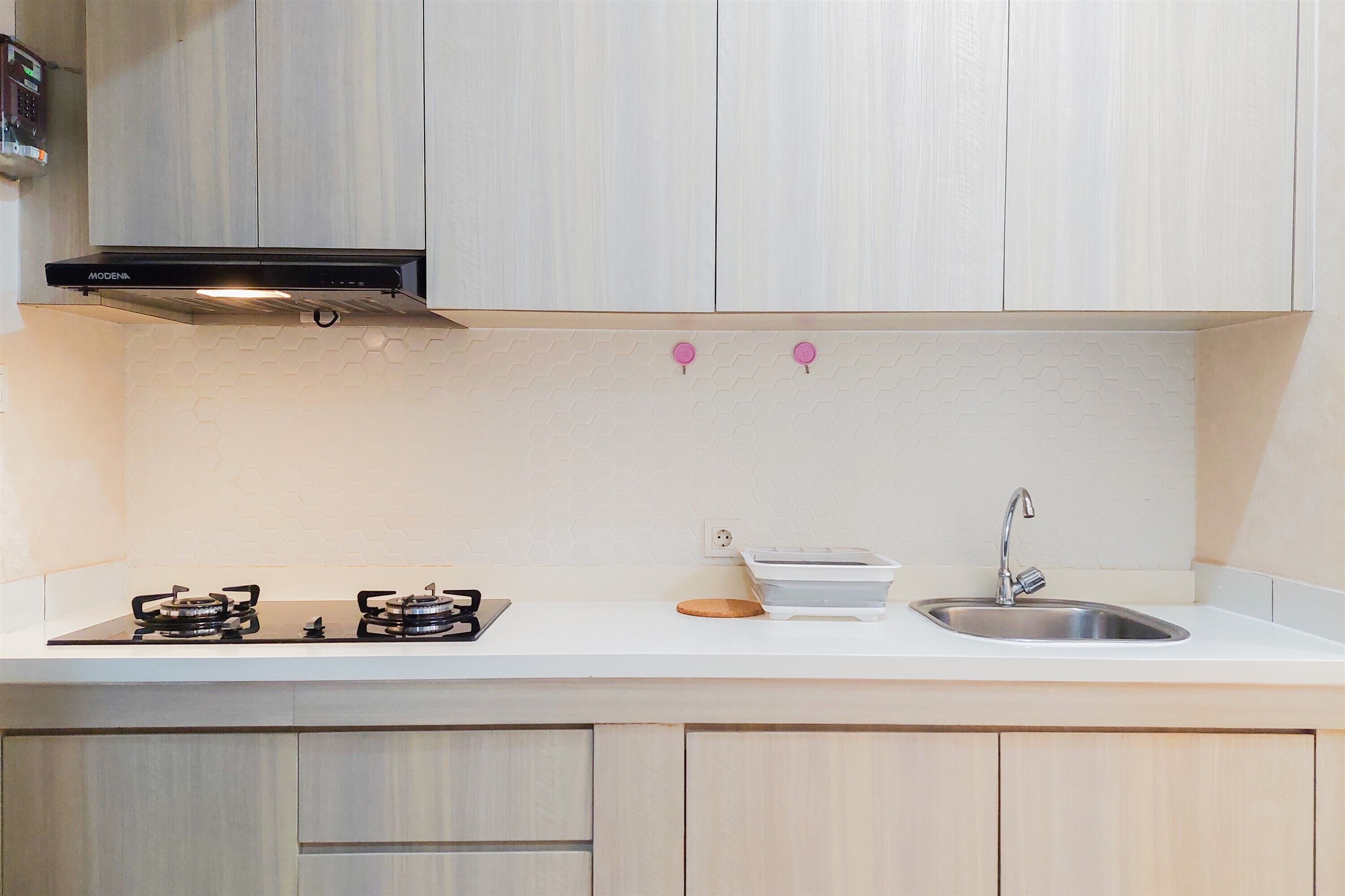 A kitchen with two gas stoves, a stainless steel sink, and a black range hood.