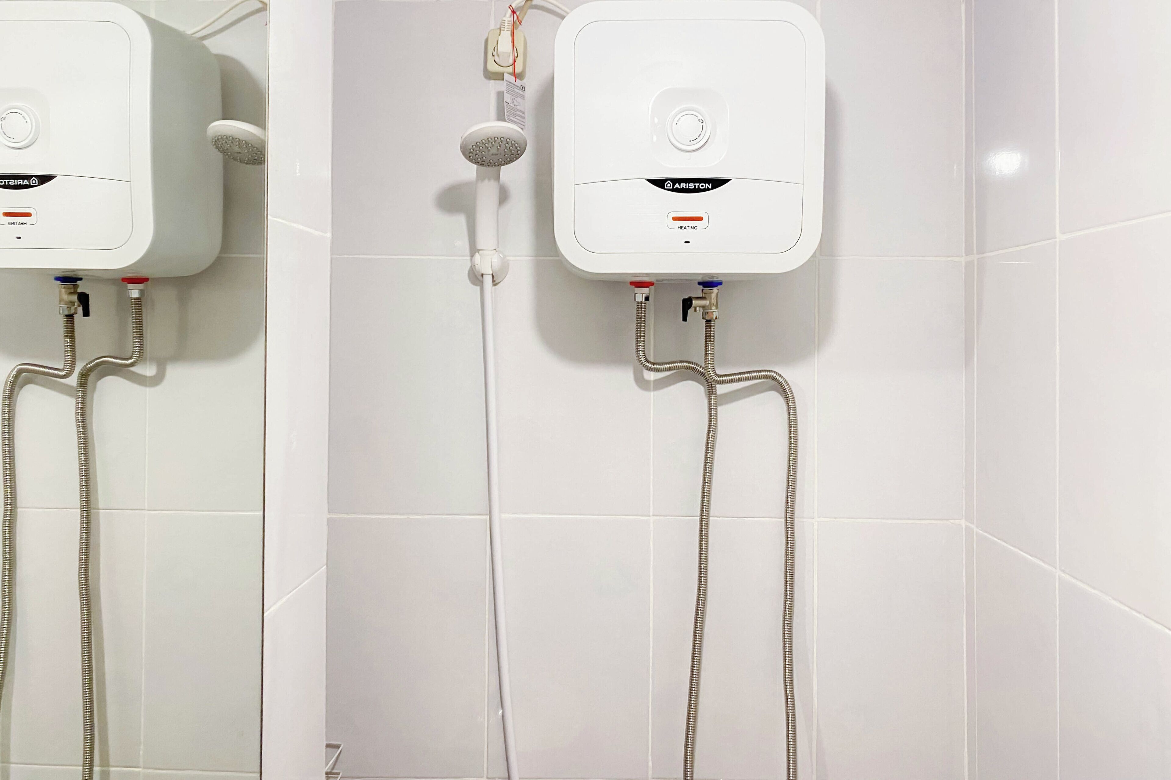 A modern bathroom with two wall-mounted shower units, each with a control panel and a handheld showerhead.