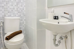 A bathroom with a toilet, a sink, and a mirror. - Good And Simply Studio Tokyo Riverside Pik 2 Apartment (Teluknaga)