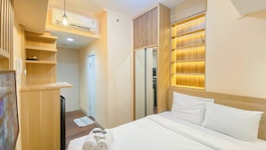 A hotel room with a bed, a wardrobe, a mirror, and a shelf with a remote control. - Good And Simply Studio Tokyo Riverside Pik 2 Apartment (Teluknaga)
