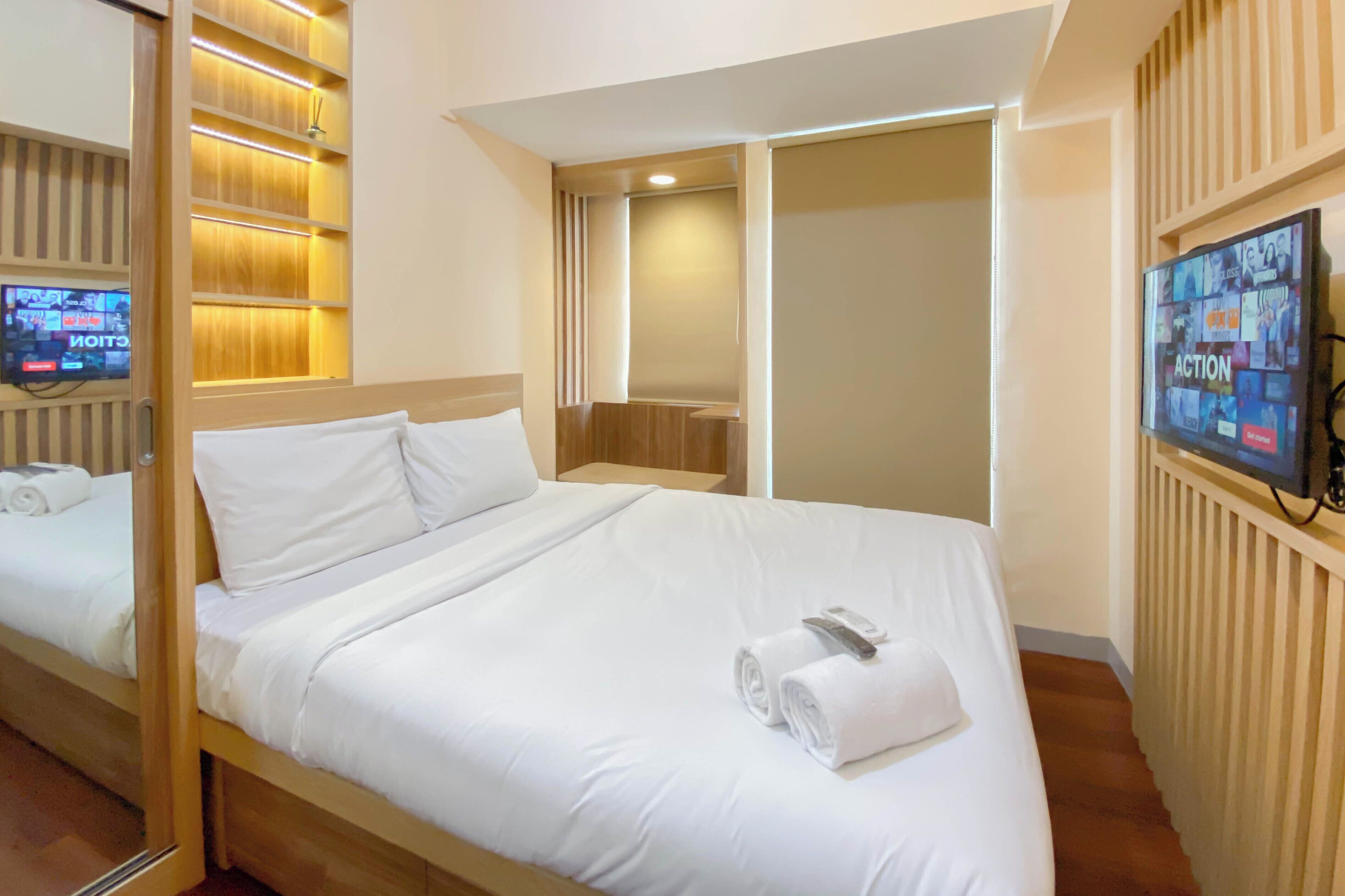 Una camera d'albergo con un grande letto, una TV a parete e un pannello decorativo in legno.