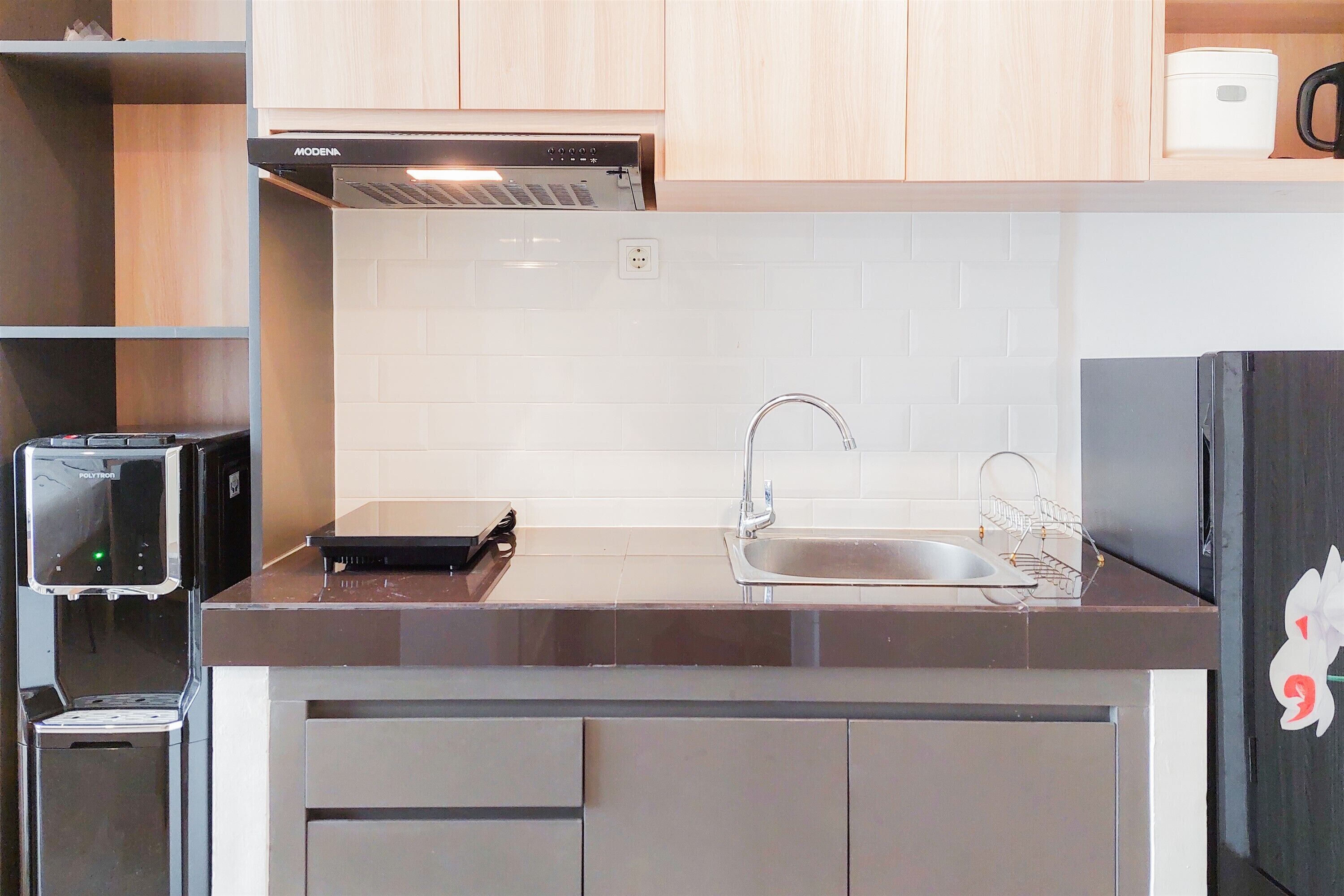 A modern kitchen with a built-in dishwasher, a stainless steel sink, and a black refrigerator.