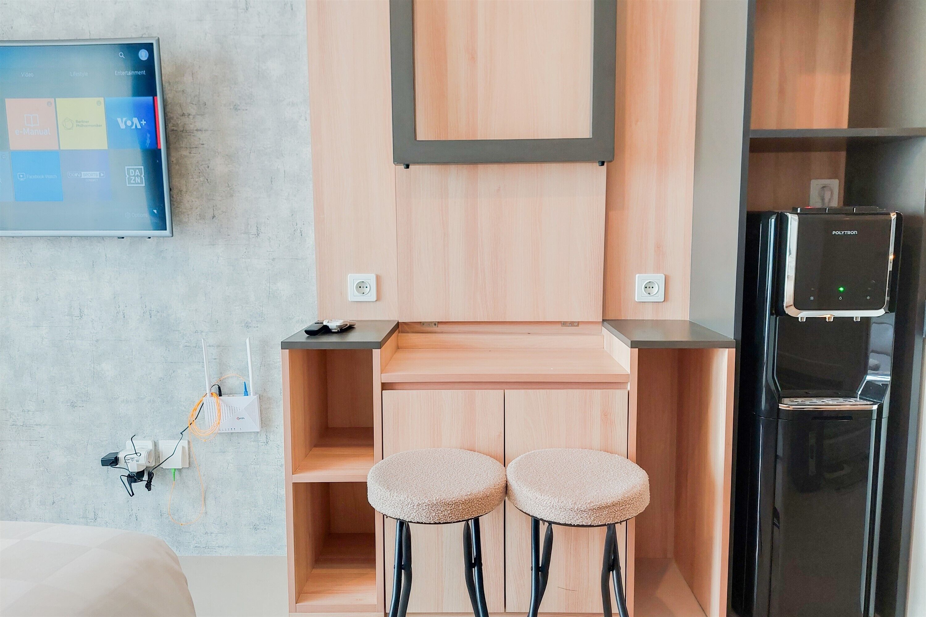 A compact kitchenette with a built-in fridge, a small bar counter, and two stools.
