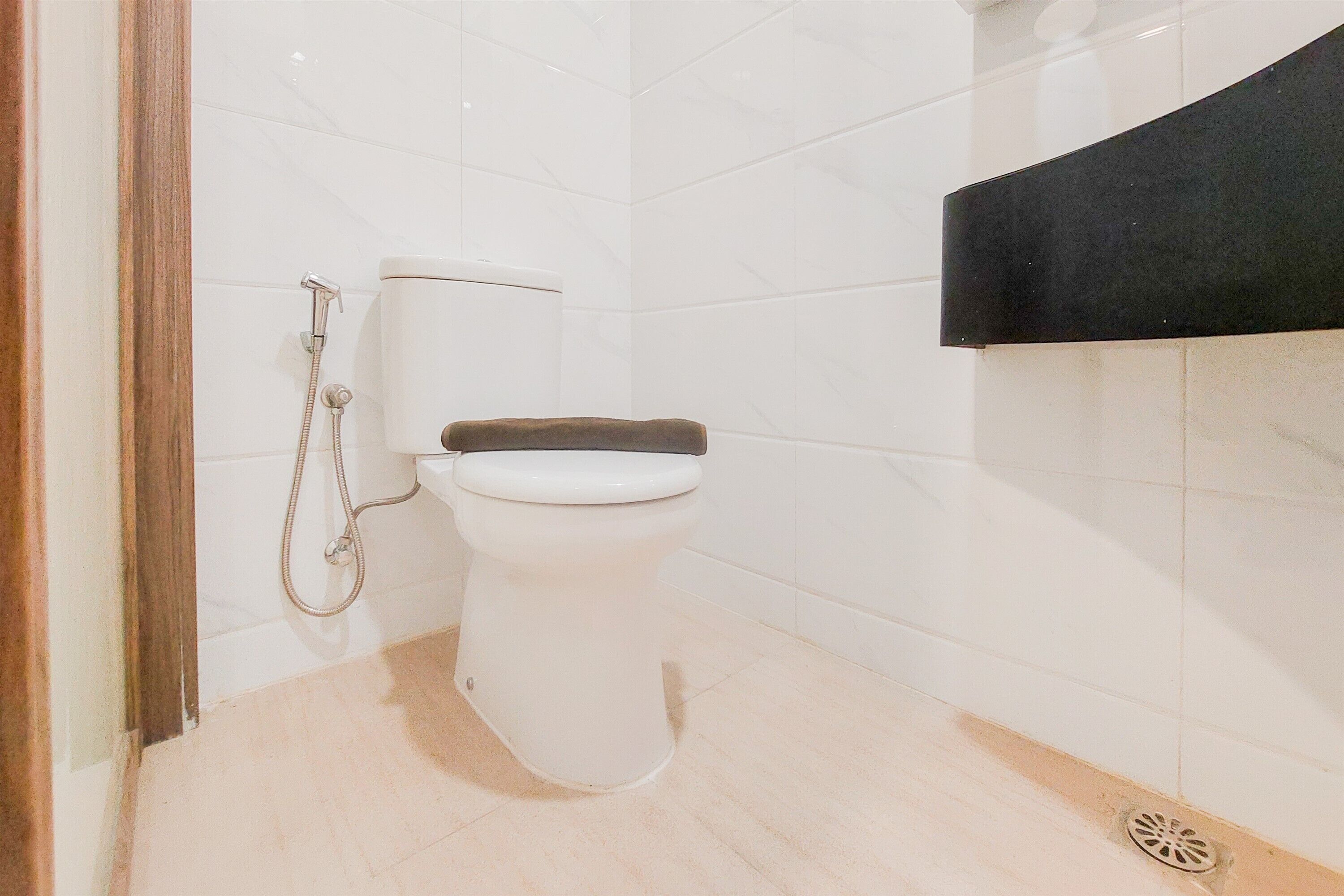 A bathroom with a toilet, shower, and a black sink counter.