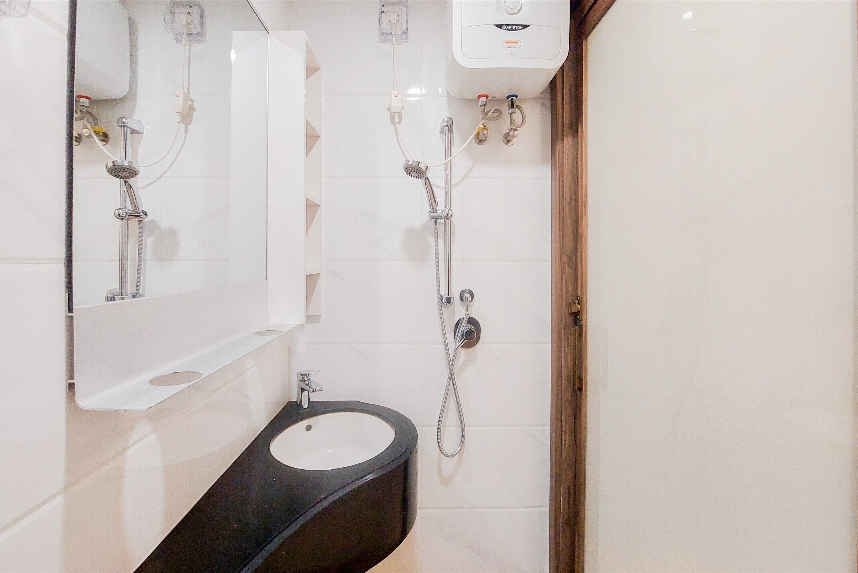 A modern bathroom with a black sink, a mirror, and a shower with a handheld showerhead.