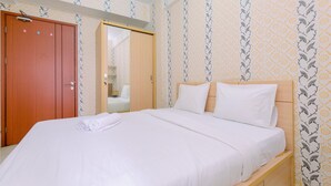 A neatly made bed with white linens, a wooden headboard, and a wooden wardrobe with a mirror. - Good Deal And Homey Studio At Margonda Residence 4 Apartment (Depok)