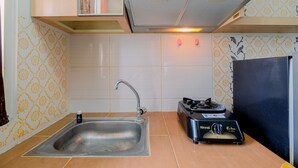 A compact kitchen with a stainless steel sink, a gas stove, and a modern range hood. - Good Deal And Homey Studio At Margonda Residence 4 Apartment (Depok)
