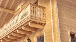 A wooden balcony with intricate railings and a window. - Glockner by Interhome (Heiligenblut)