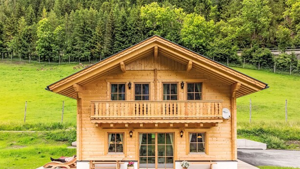 A wooden chalet with a balcony, large windows, and a sign indicating it is a guesthouse. - Glockner by Interhome (Heiligenblut)