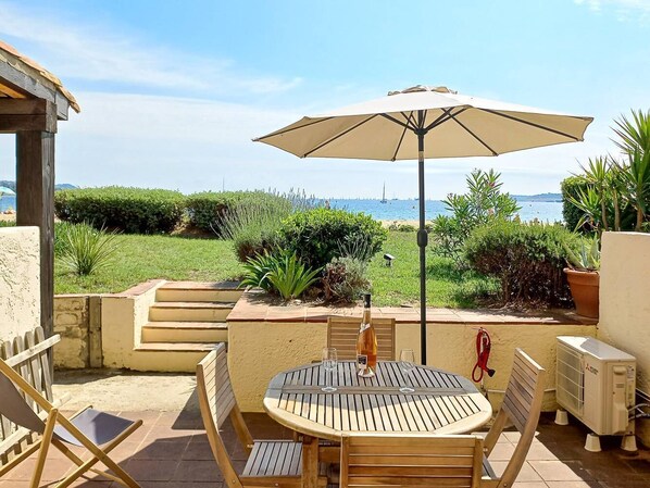 Enjoy al fresco dining with a view of the serene sea landscape from this outdoor patio, featuring a round table and comfortable seating.