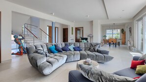 Amplia sala de estar con sofá modular, mesa de comedor y escalera.