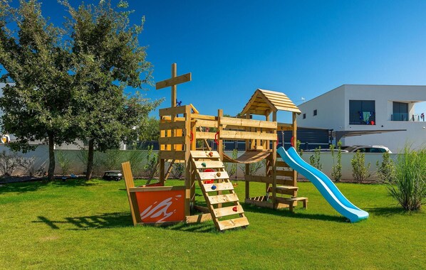 Un parque infantil de madera con tobogán y escaleras de acceso.