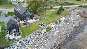 Una casa moderna con una amplia terraza, un jacuzzi y un sendero de piedra que lleva a la playa.
