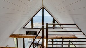 Habitación con techos altos y un ventanal grande que ofrece vistas al mar.