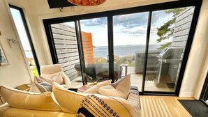Una sala de estar moderna con un sofá, una mesa de centro de madera y un ventanal con vistas al mar.