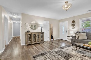 A spacious living room with hardwood flooring, a large sofa, a coffee table, and a fireplace. - 3BR - Pet-Friendly & Close to Downtown Greer (Greer)