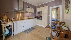 Een kleine keuken met witte kastjes, een magnetron en een koffiezetapparaat. Er is een houten eettafel met stoelen en een klein vloerkleed.