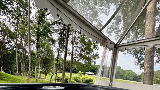 A hot tub with a glass enclosure, surrounded by trees and a grassy area. - Countryside Getaway Green UniqueDomeA/serene farm retreat (Snow Camp)