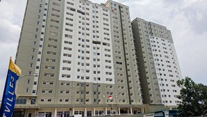 A multi-story residential building with balconies, a flag, and a street sign. - Good Price And Homey 2Br At Loftvilles City Apartment (South Tangerang)