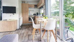 Een moderne keuken met houten kastjes, een inbouwoven en een eethoek met witte stoelen en een tafel.