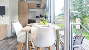 Een moderne keuken met houten kasten, een eettafel met stoelen en uitzicht op de omgeving.