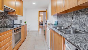 Una cocina moderna con armarios de madera, encimeras de granito, horno empotrado, microondas y lavavajillas.