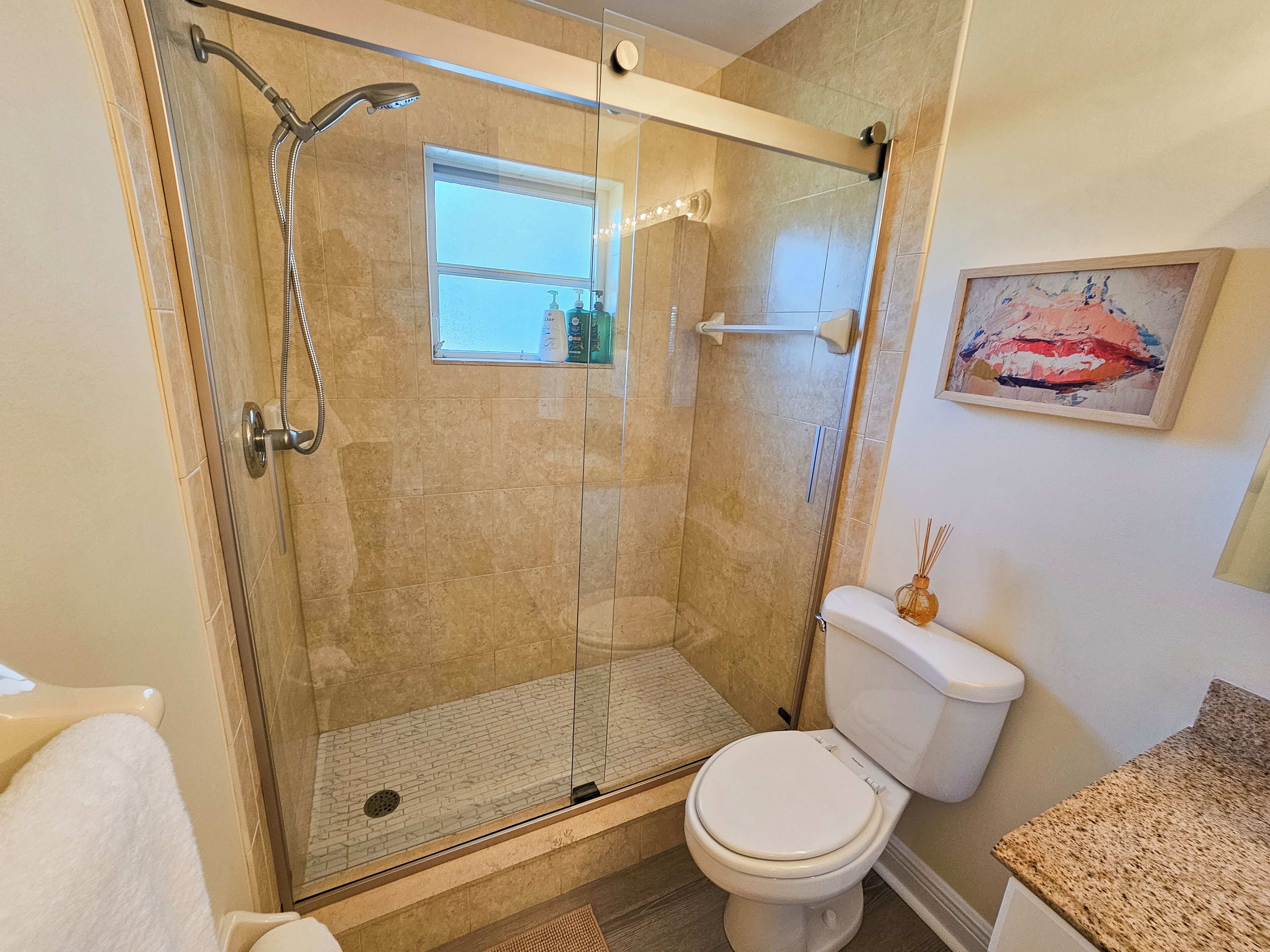 A modern bathroom with a glass-enclosed shower, a toilet, and a sink.