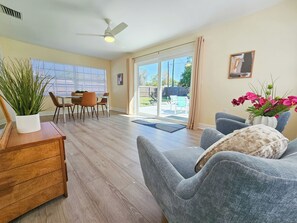 Ein geräumiges Wohnzimmer mit grauem Sofa, Holz-Couchtisch und einem Essbereich mit Tisch und Stühlen.