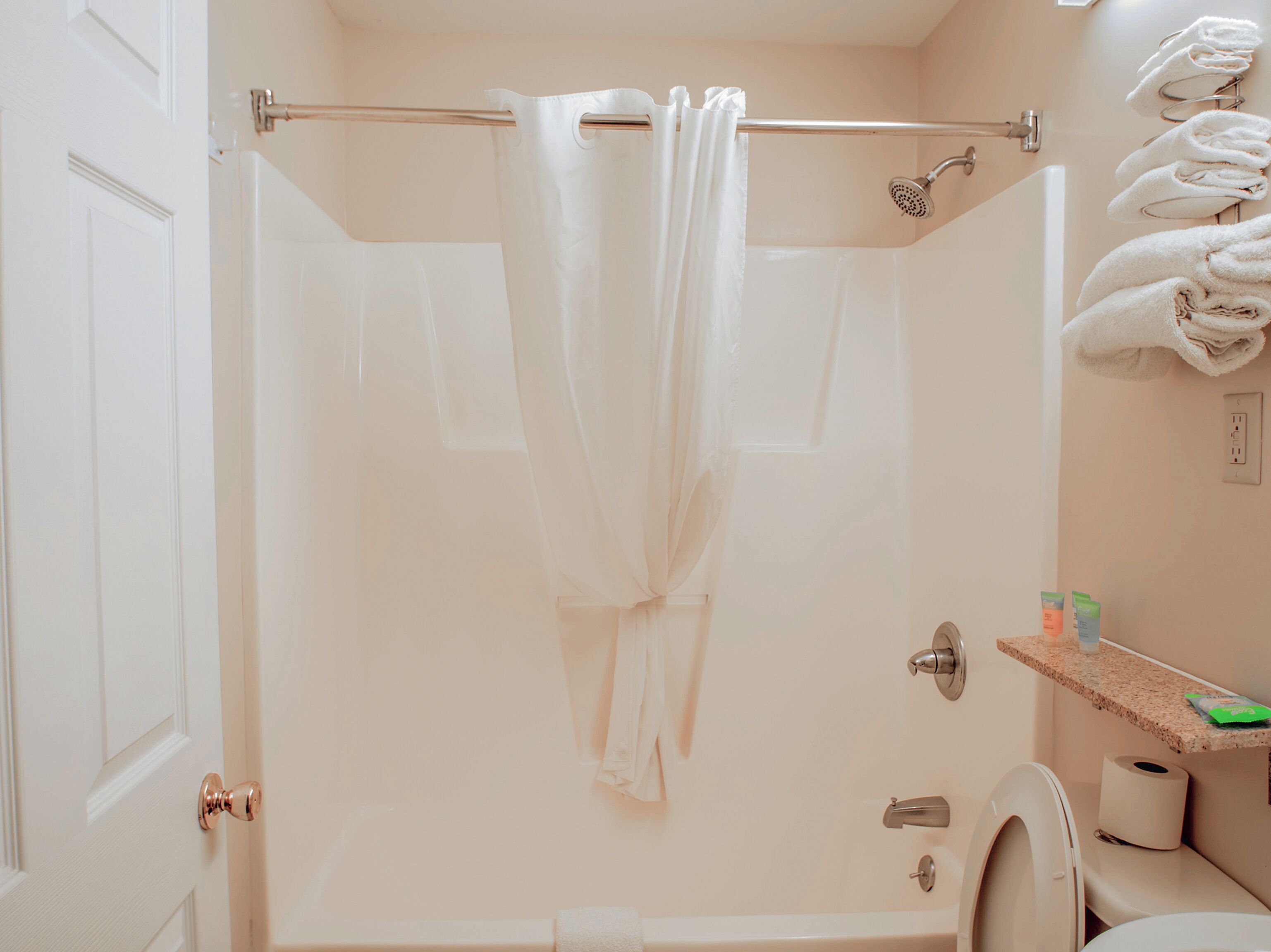 A bathroom with a shower curtain, a toilet, a towel rack, and a shelf with toiletries.