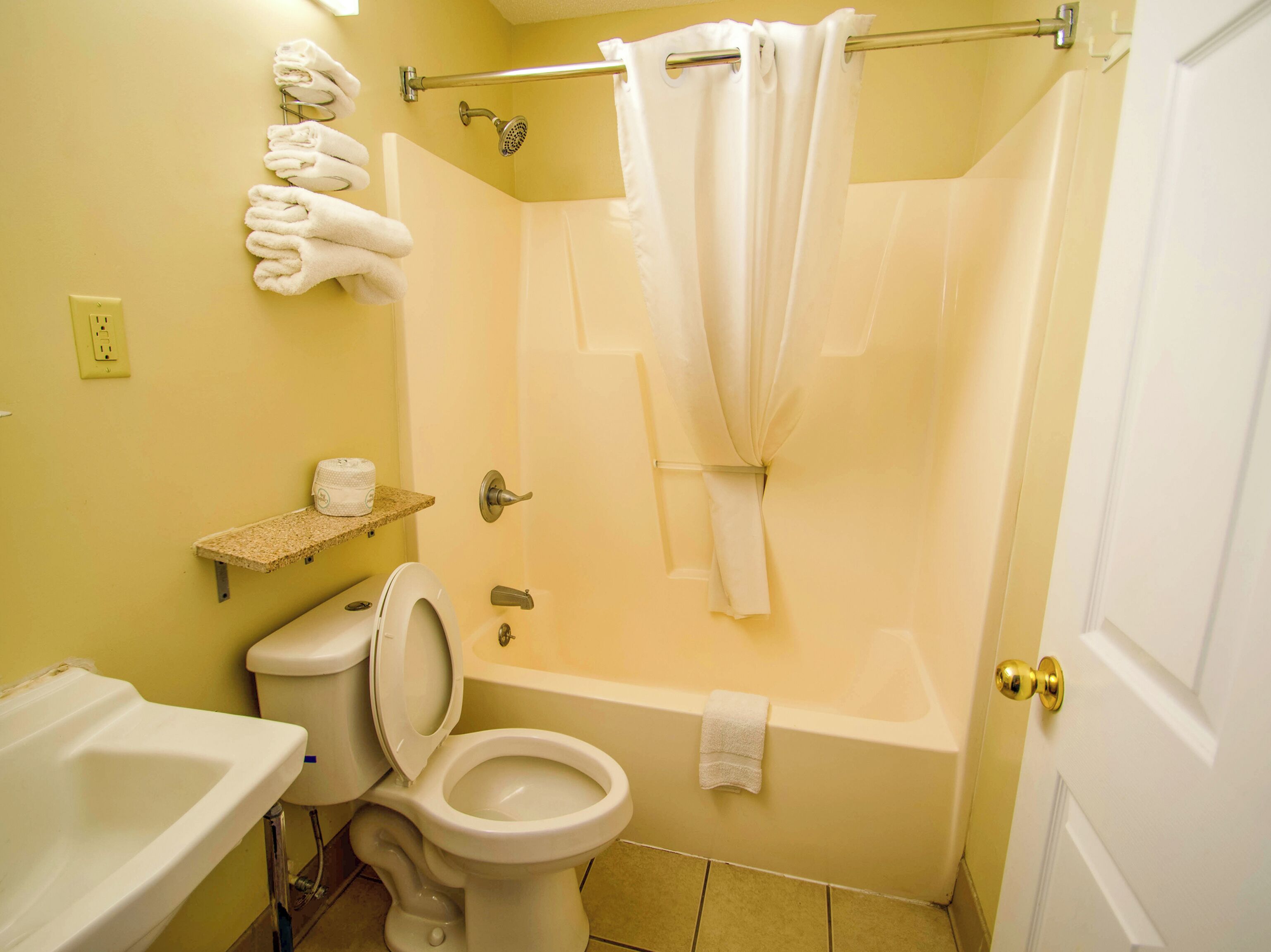 Une salle de bain équipée de toilettes, d’un lavabo, d’une baignoire et d’un rideau de douche.