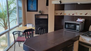Une cuisine dotée d’une grande fenêtre, d’un four à micro-ondes, d’une cuisinière et d’un coin repas avec des chaises.