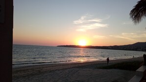 A beach with a sunset, calm sea, and a few people walking. - Dos recamaras en la playa conveniente (bucerias)