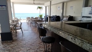 A kitchen area with a stone-tiled floor, a bar with stools, and a view of the ocean. - Dos recamaras en la playa conveniente (bucerias)