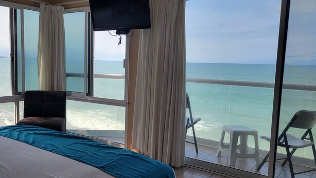 Een kamer met een bed, een televisie en uitzicht op zee.