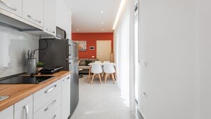 Uma cozinha moderna com armários brancos, bancada de madeira e forno embutido.
