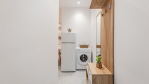 A modern bathroom with a white sink, a wooden vanity, a washing machine, and a mirror.
