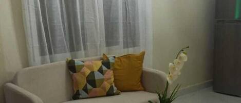 A living room with a beige sofa, a wooden coffee table, and a potted plant.