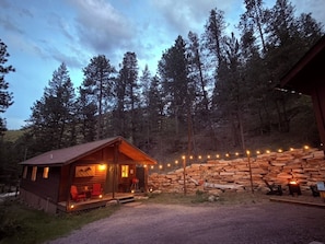 Une cabane avec une véranda, un mur en pierre et un espace aménagé pour faire un feu de camp.