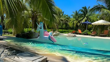 A pool area with a unicorn float, lounge chairs, and palm trees.