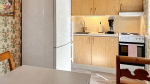 Una cocina con armarios de madera, un refrigerador blanco, un lavamanos, una cafetera y una estufa.