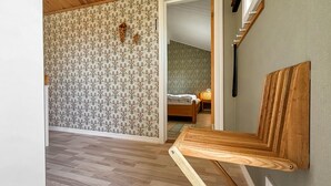 Una habitación con un banco de madera, una cama y un papel tapiz estampado.