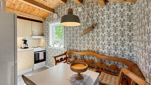 Una cocina con un banco de madera, una mesa con un cuenco y una ventana con vistas al verdor.