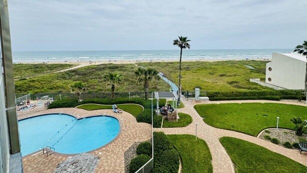 A pool area with a view of the beach and ocean. - Two Bedroom One Bath Beachfront Condo (South Padre Island)