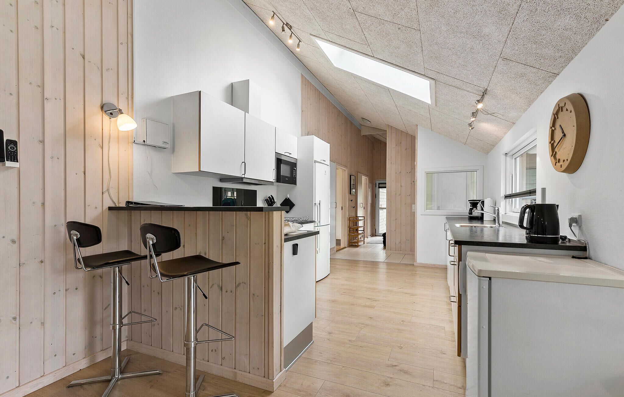 A modern kitchen with high ceilings, wooden paneling, and a skylight.
