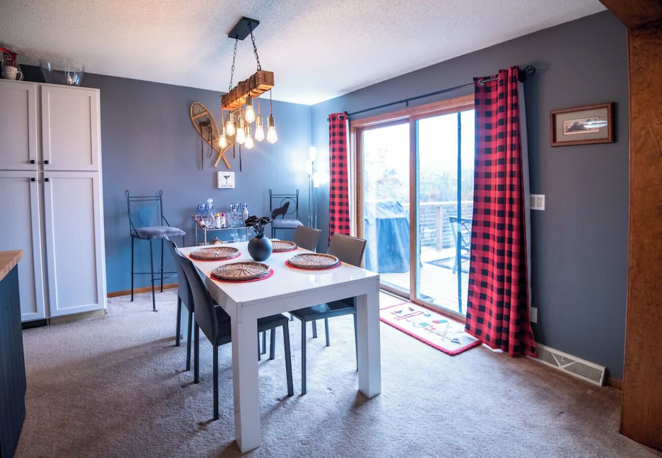 Un espace repas avec une table blanche, des chaises et un luminaire suspendu.